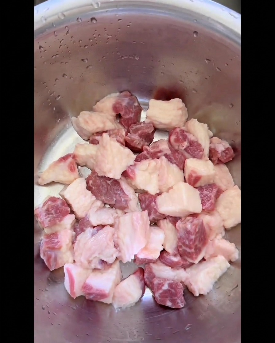 Raw beef brisket fat cleanly cut into uniform small squares and placed inside a stainless steel mixing bowl.