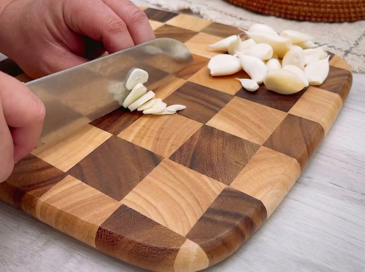 Finely minced garlic pieces spread across a wooden cutting board.