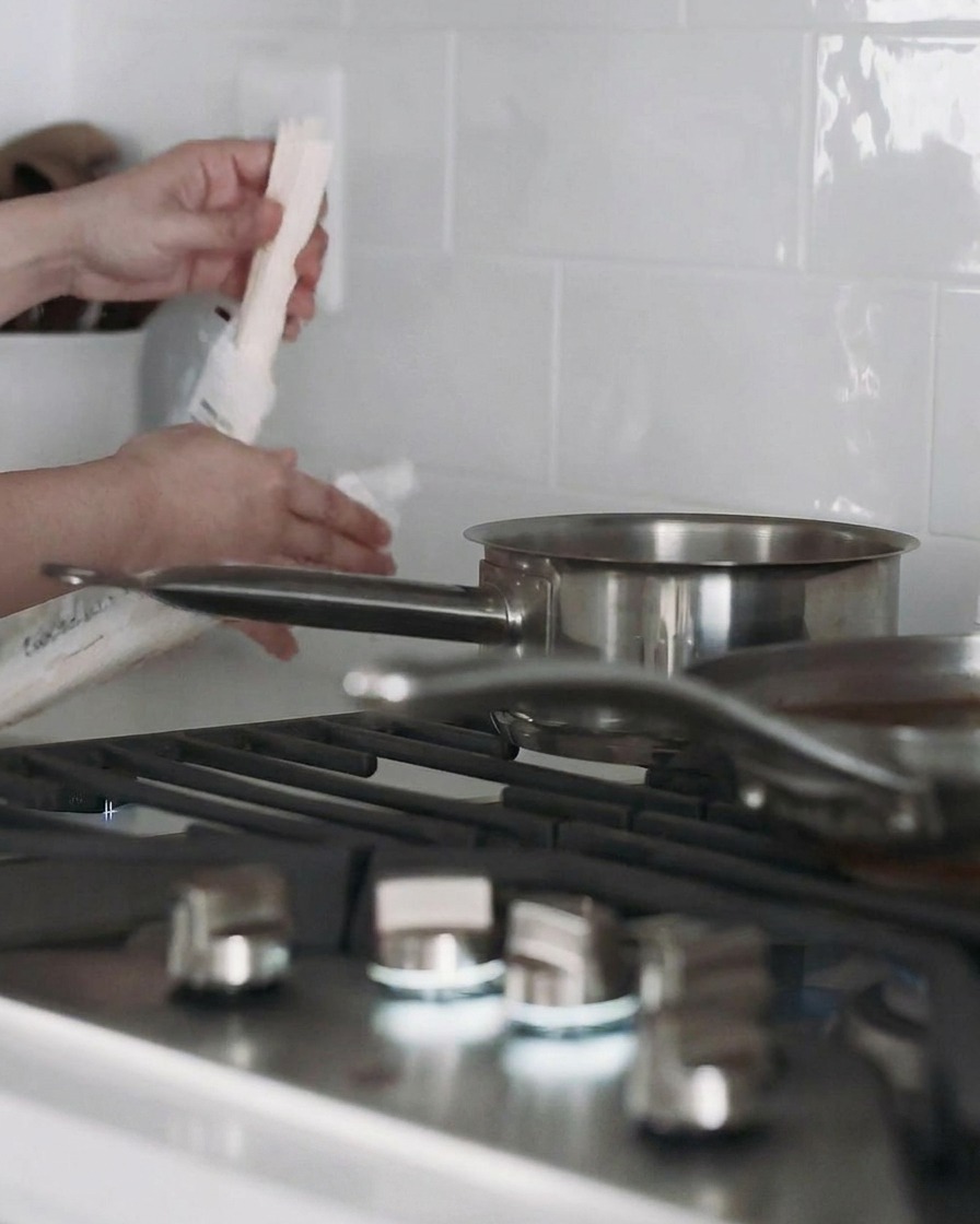 A pot of water on the stove with udon noodles cooking inside.