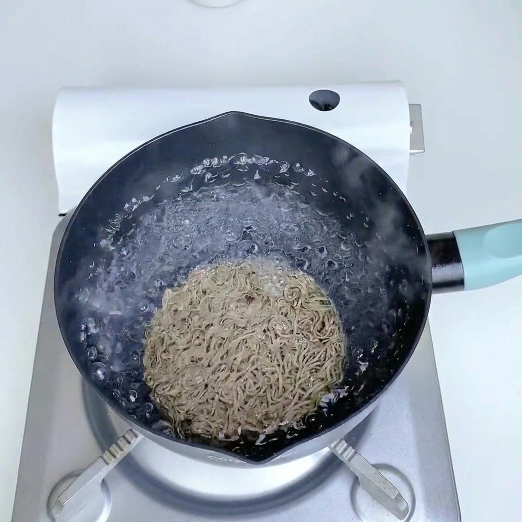 Buckwheat noodles cooking in a pot of boiling water.