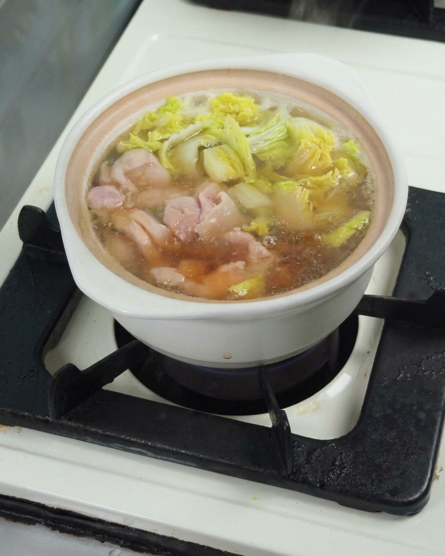 Soy sauce being drizzled into the simmering broth, seasoning the one-pot meal mixture.