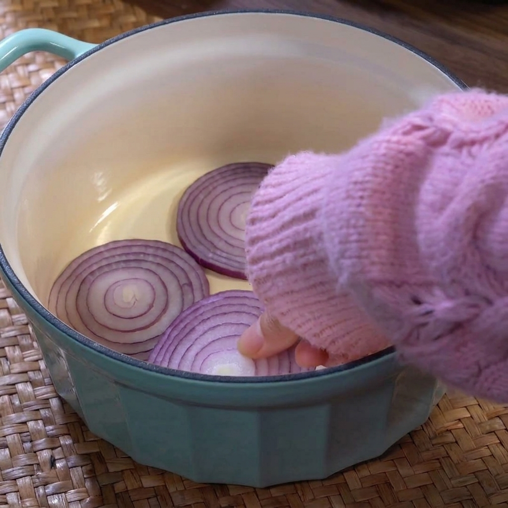 Light blue pot layered with onions, cabbage, and sliced lotus root at the base.
