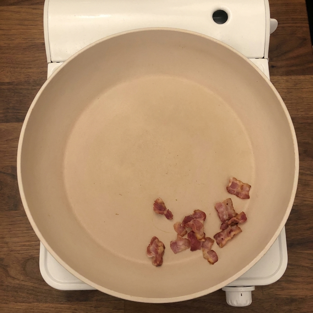 Fresh chopped onions and celery being added to the pan with crispy bacon pieces.