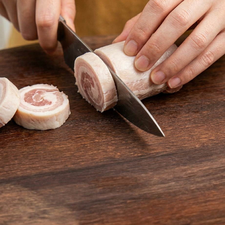 Bacon slices being chopped into small pieces on a wooden cutting board.