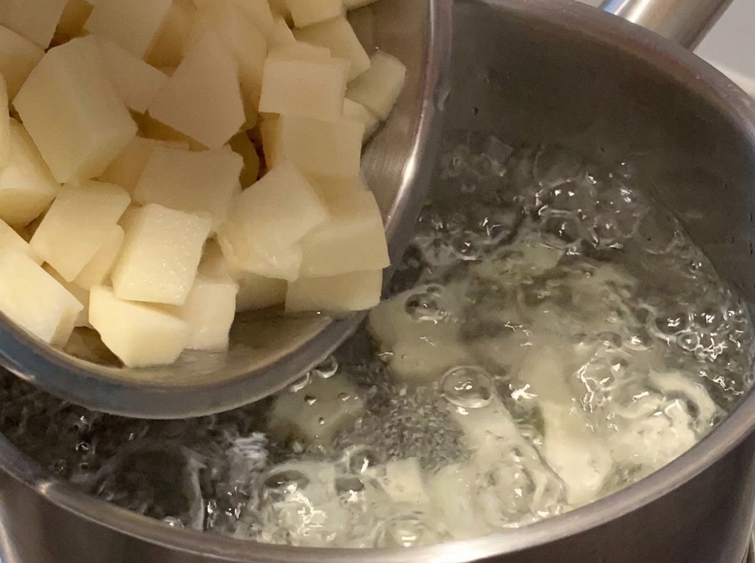 Diced potatoes boiling in a pot of water on the stove.