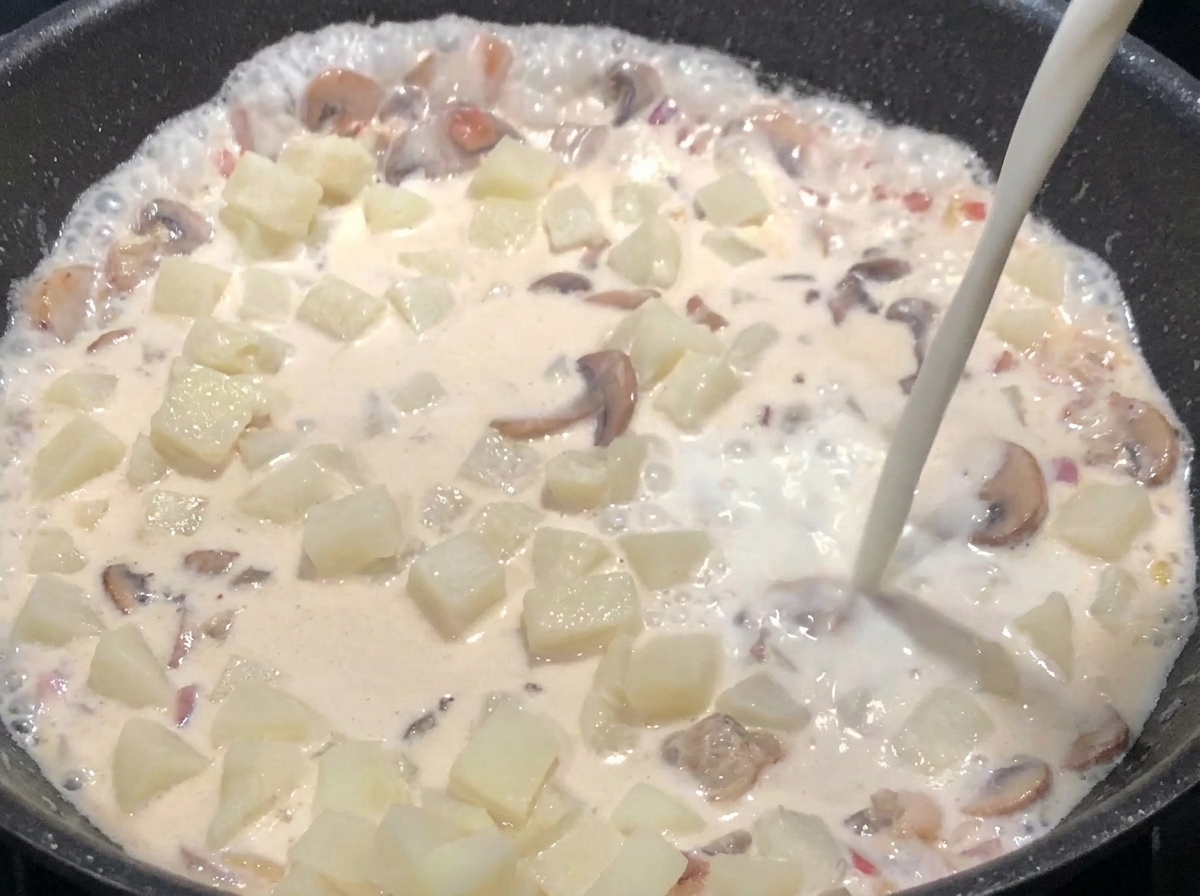 Milk being added to the pan until the ingredients are submerged, while the mixture simmers and thickens.