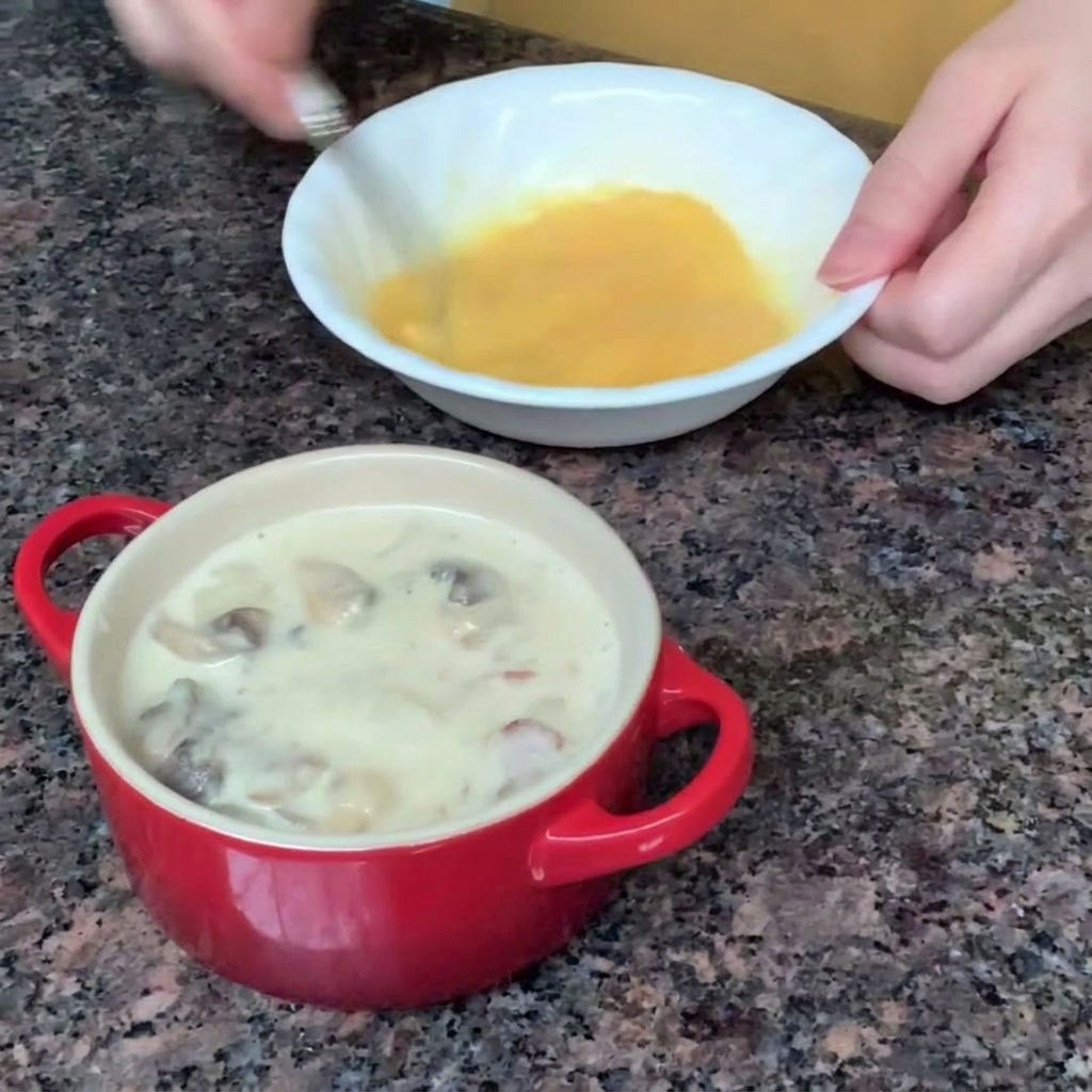 An egg being beaten with a fork in a small white bowl.