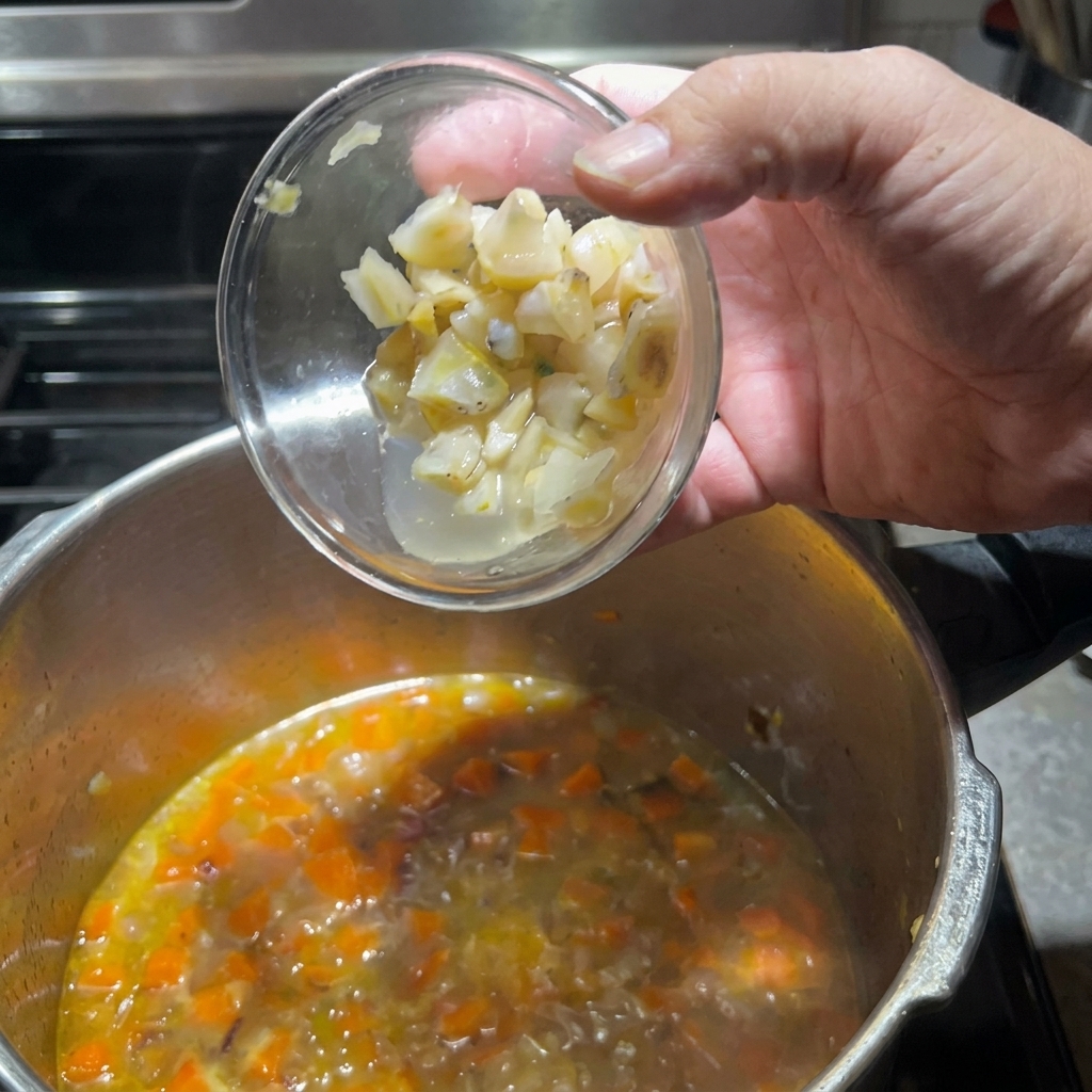 Adding prepared clam pieces into the pot with vegetables.