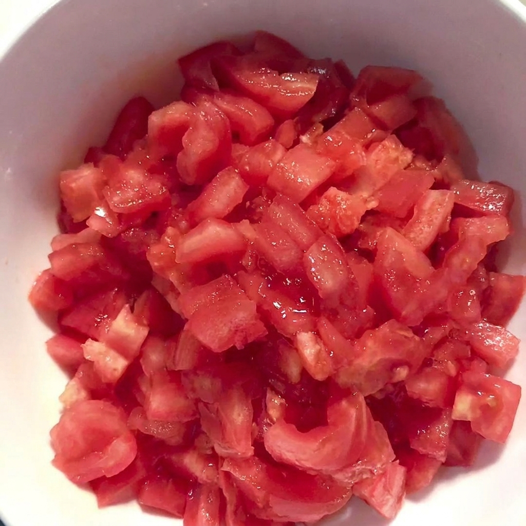A white bowl filled with freshly diced, peeled tomatoes.