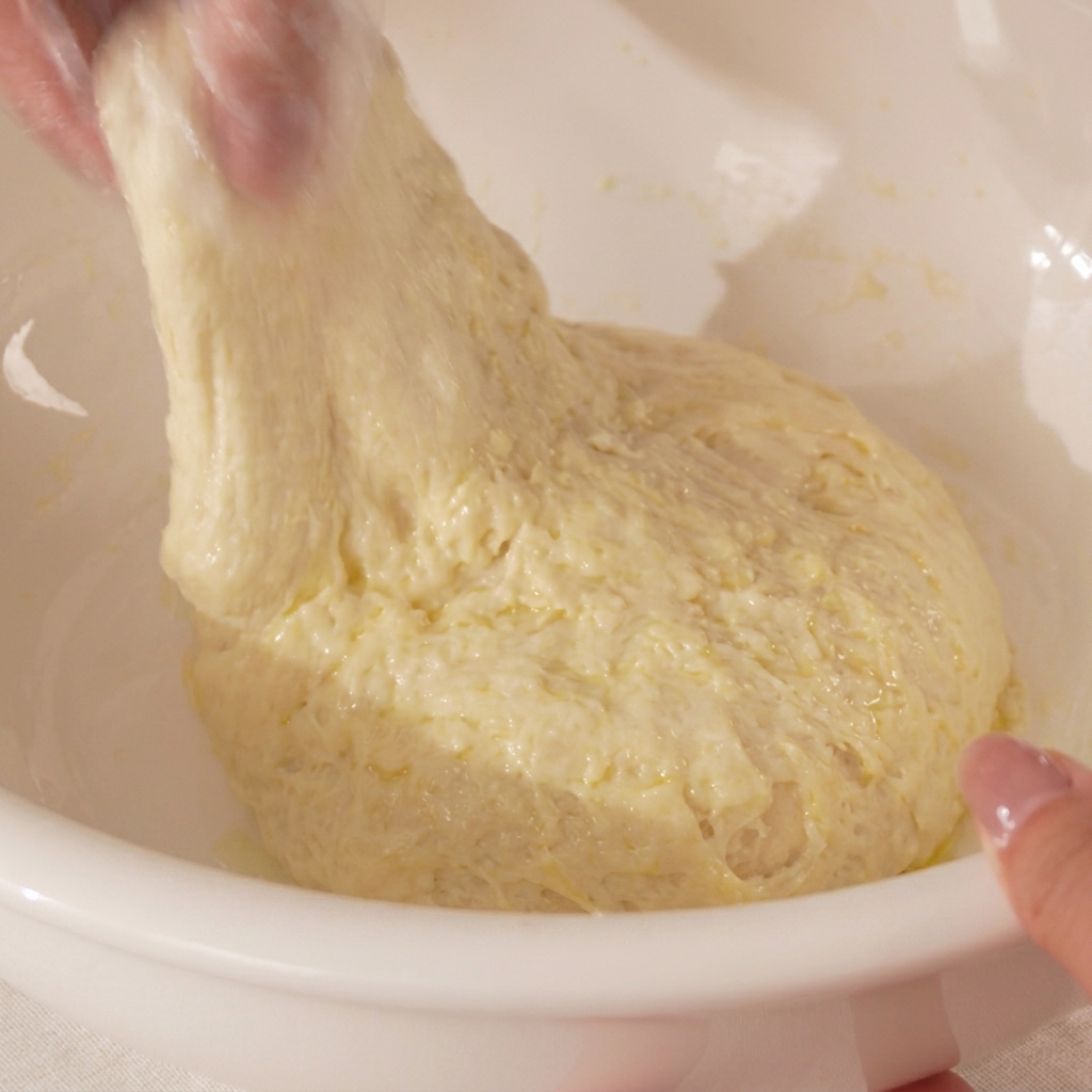 A close-up view of hands stretching the pizza dough and folding it over onto itself