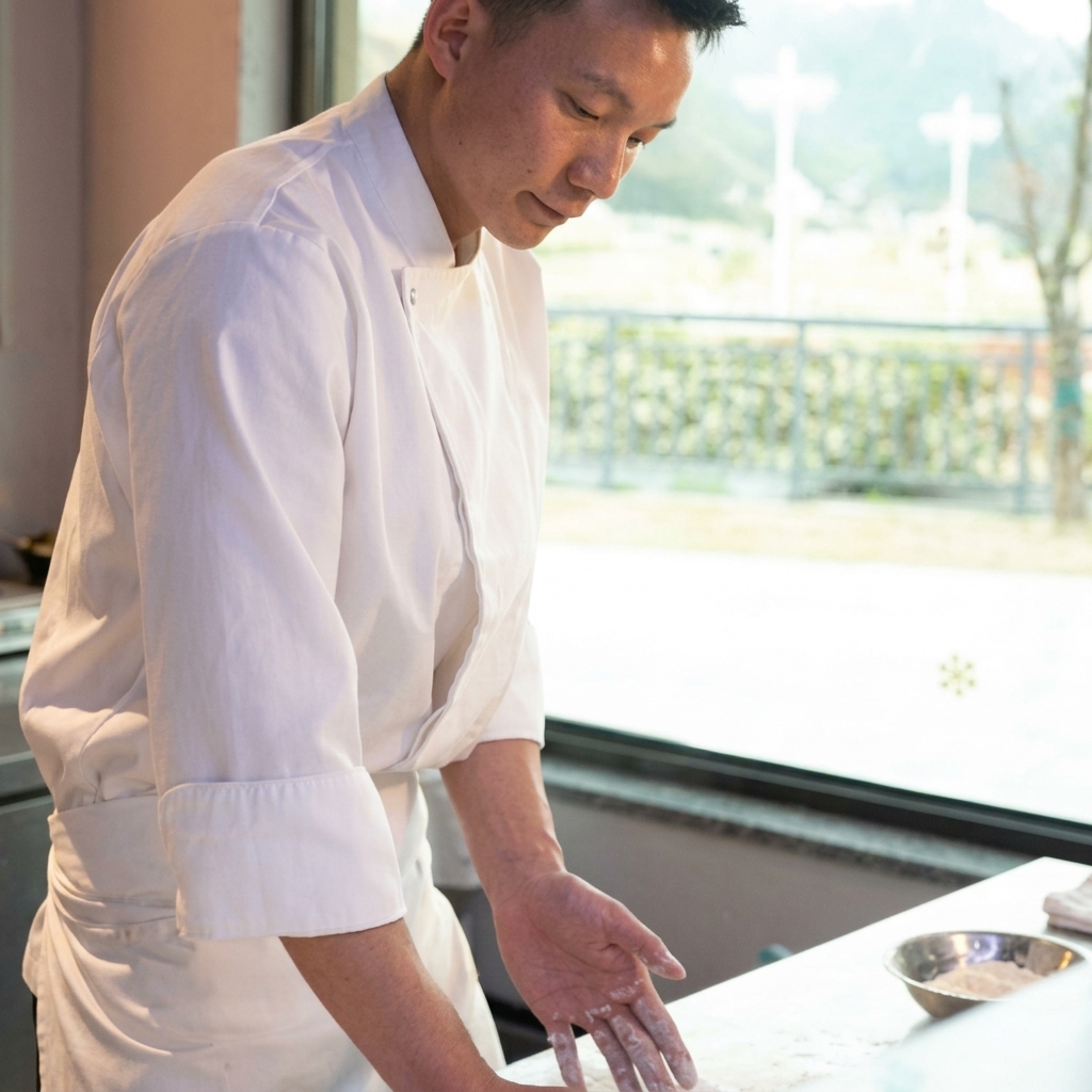 Hands pressing and stretching a pizza dough ball on a cool marble countertop.