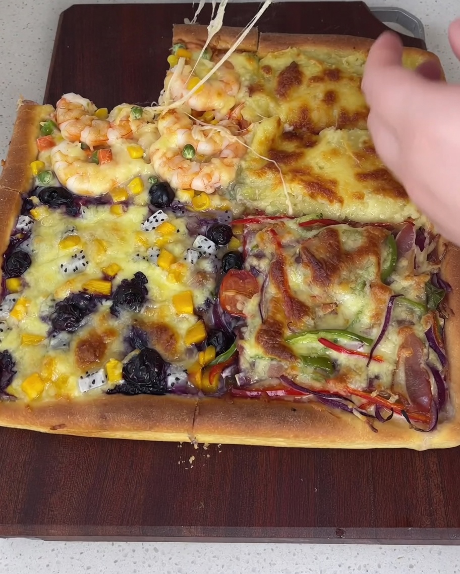 Brushing white salad dressing on two quarters and red tomato sauce on the remaining two quarters of a par-baked square pizza crust.