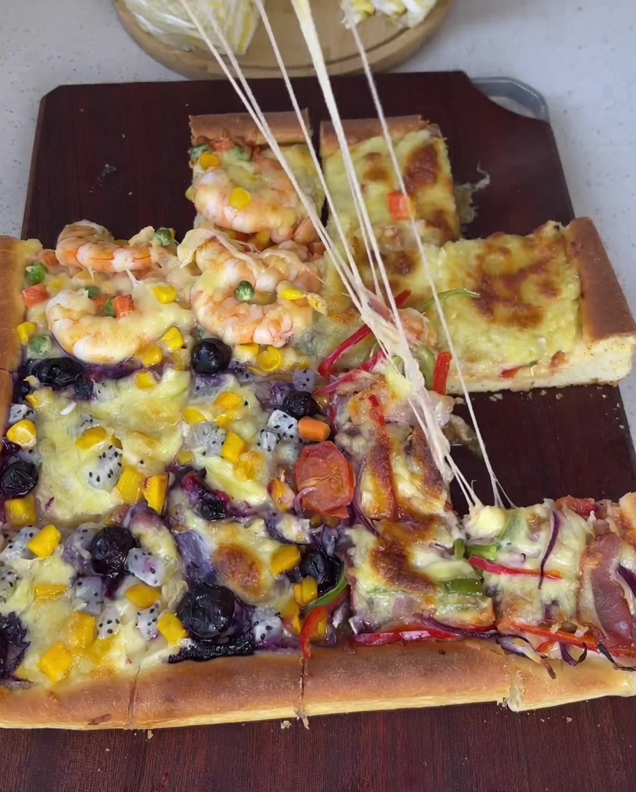 Raw peeled shrimp distributed over a section of the pizza along with mixed peas, corn, and diced carrots.