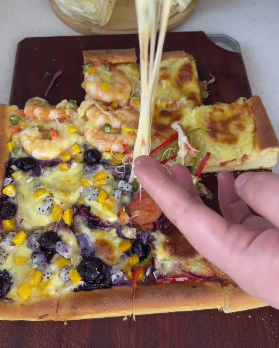Creamy durian flesh being spread evenly across the fourth section of the pizza dough using a spoon.