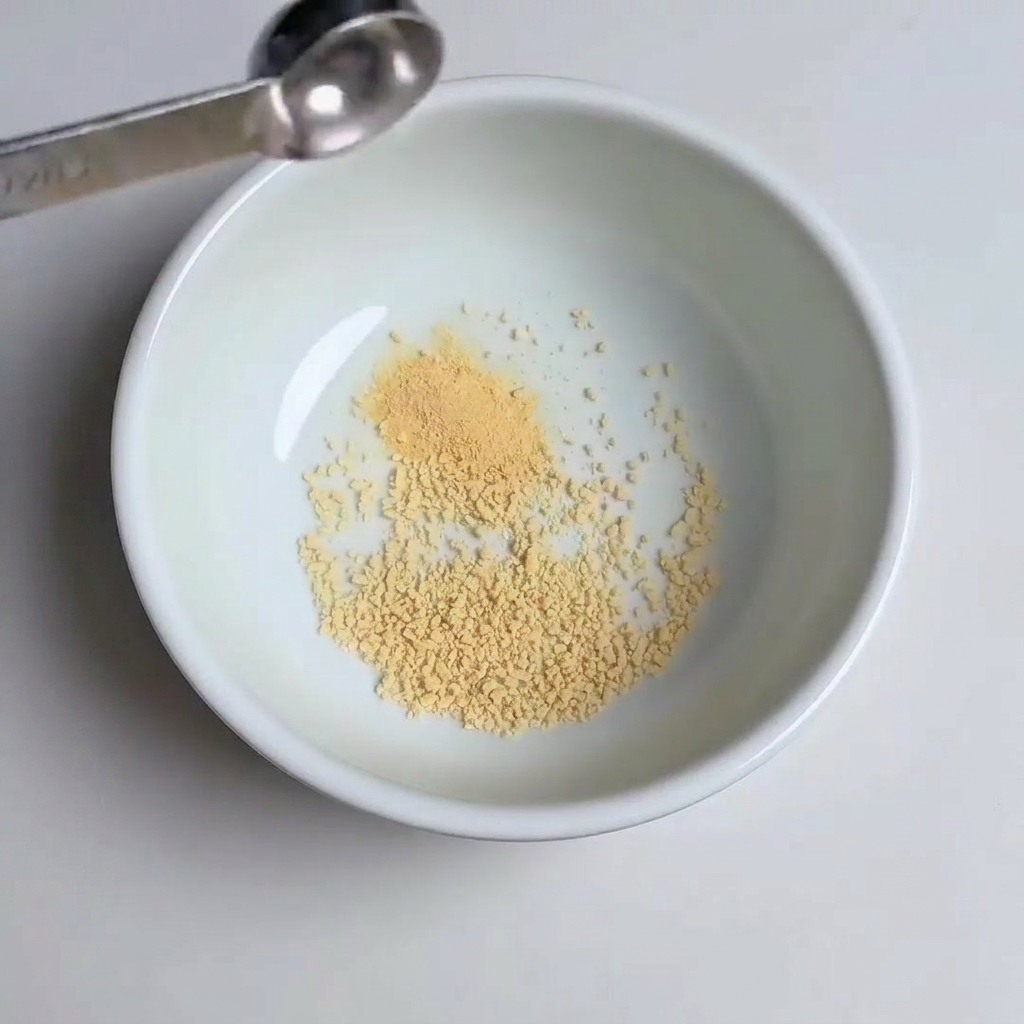 Measuring spoons adding garlic powder, sugar, and gochujang paste into the bowl.