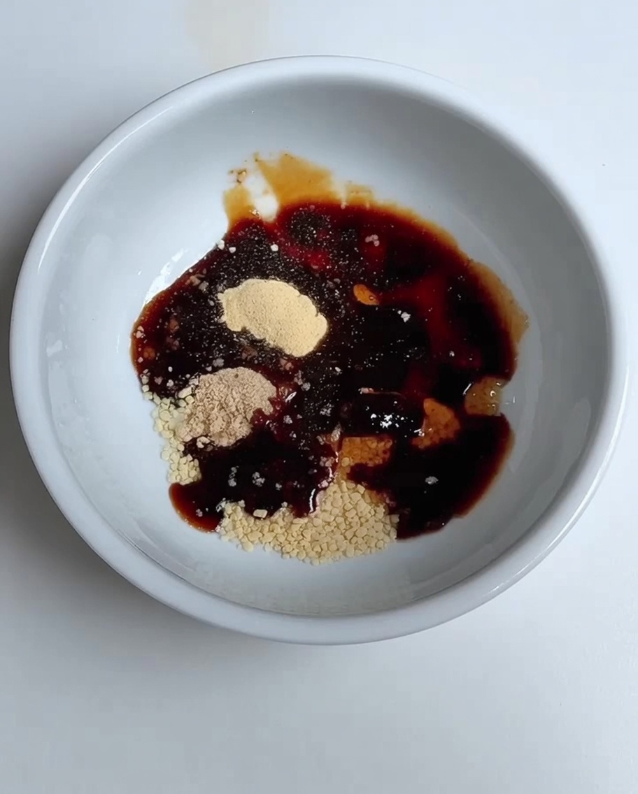 Water being poured into the bowl containing the soy sauce and seasoning blend.