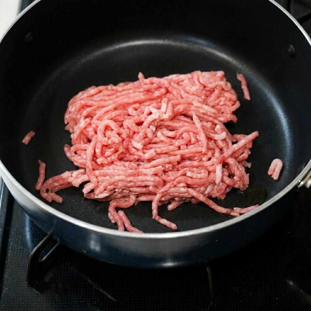 Ground pork sizzling in a pan with spicy bean paste and garlic.
