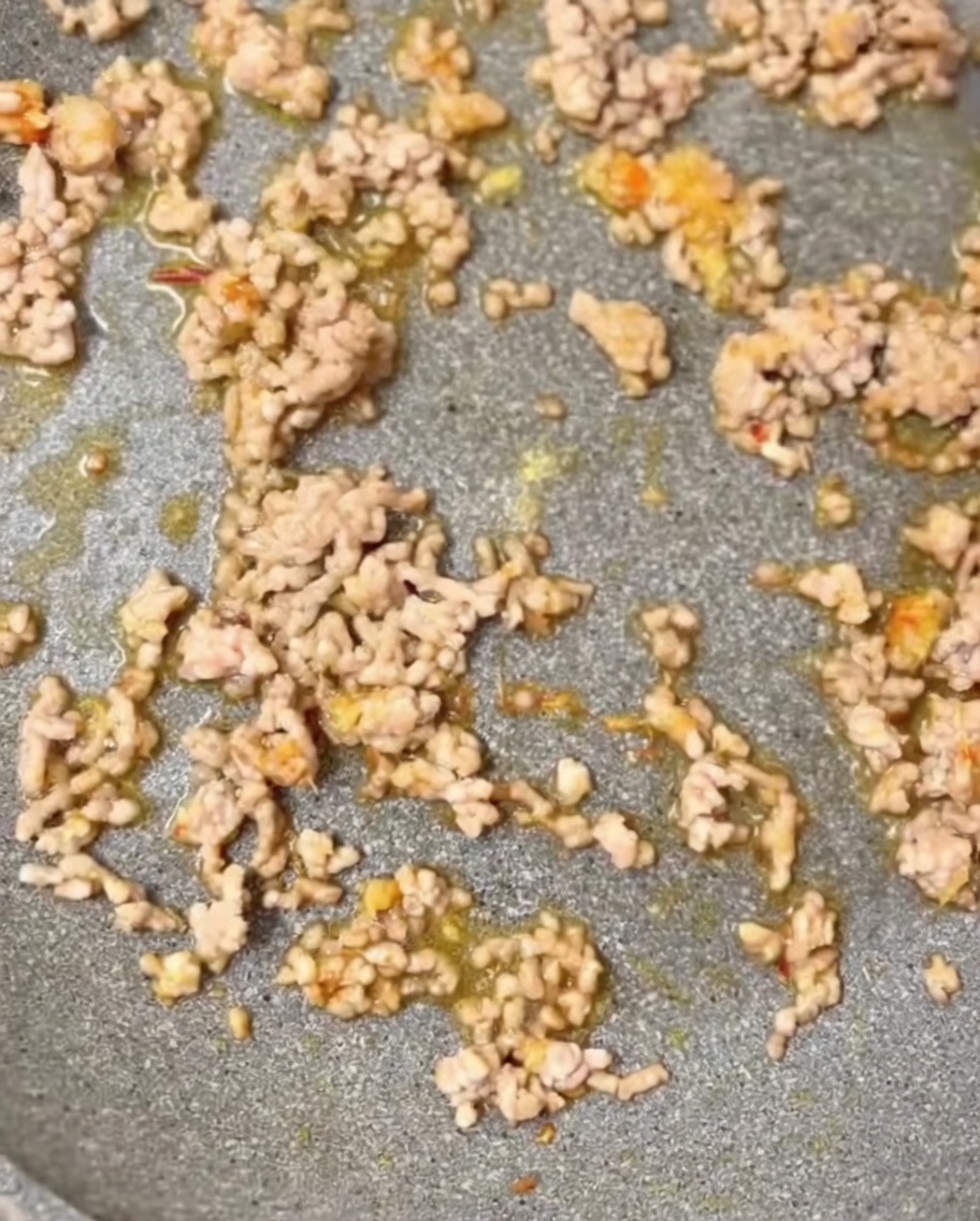 Seasonings including ground sesame and chicken bouillon being added to the pan.