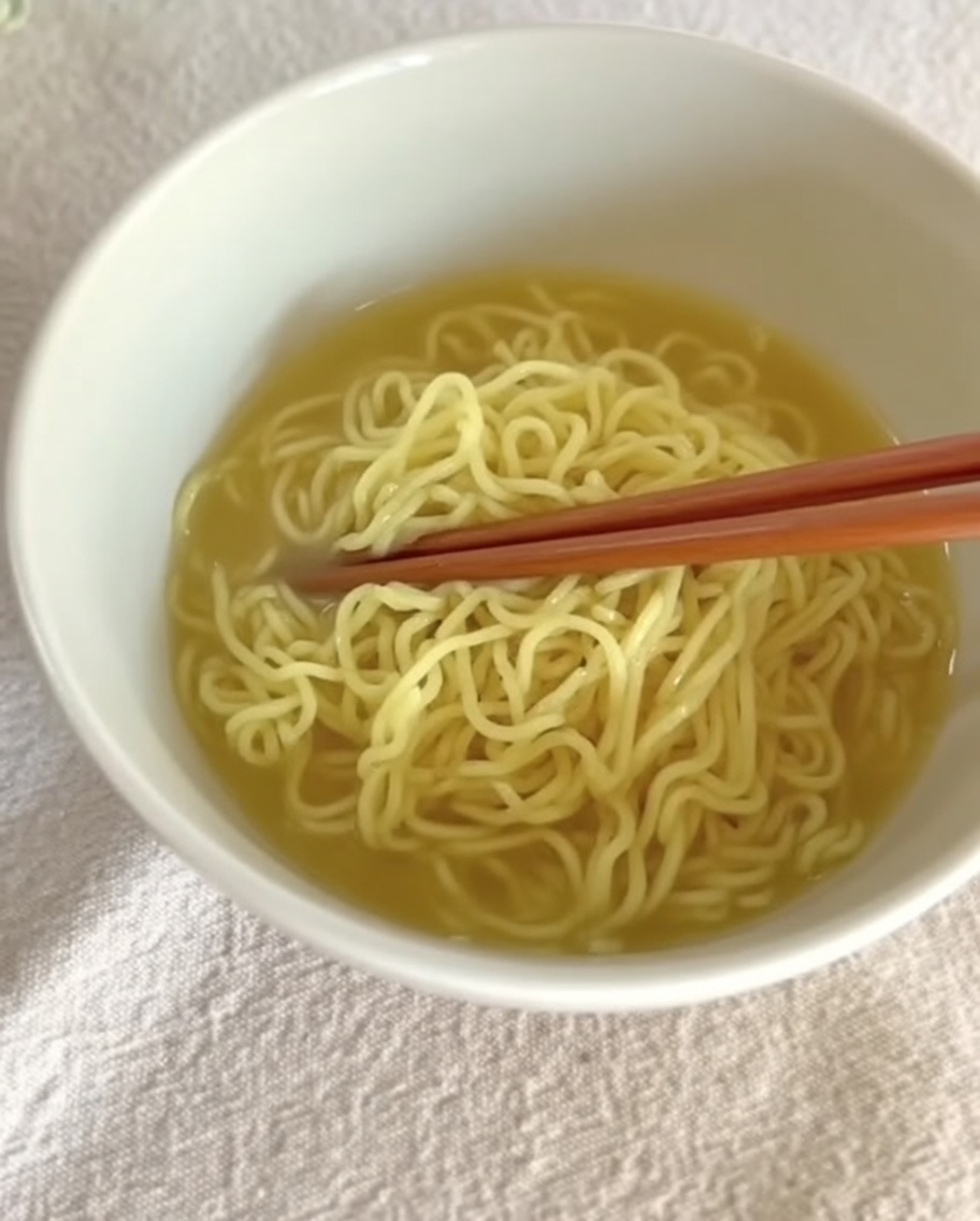 Creamy Tantanmen broth being poured over prepared noodles in a bowl.