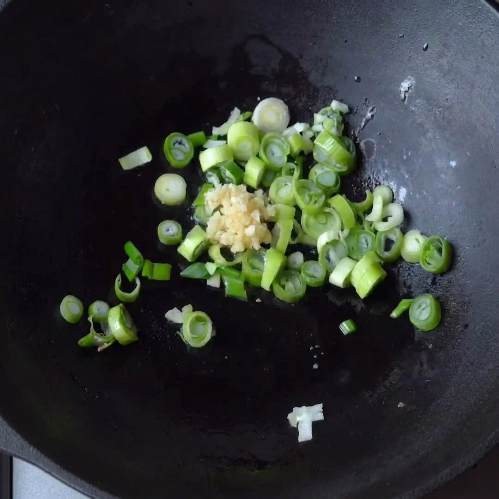 Minced garlic being added to the pan with already cooking green onions.