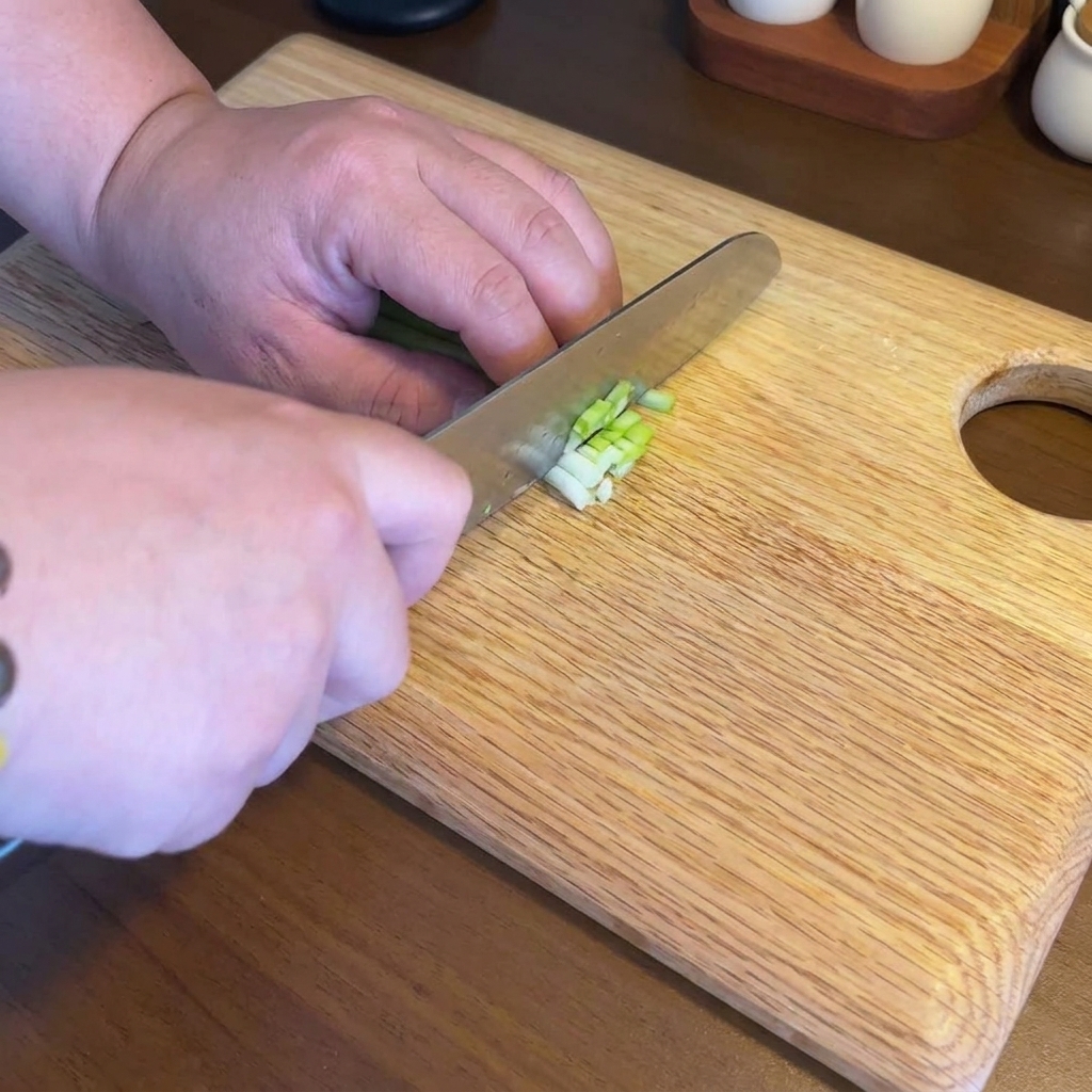 Finely minced garlic, ginger, and green onions arranged on a wooden cutting board.