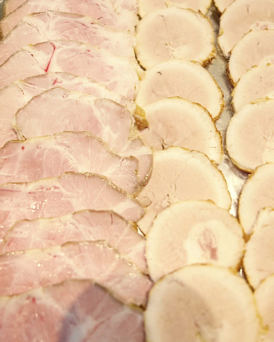 Thinly sliced chashu pork rounds arranged on a tray, ready for serving.