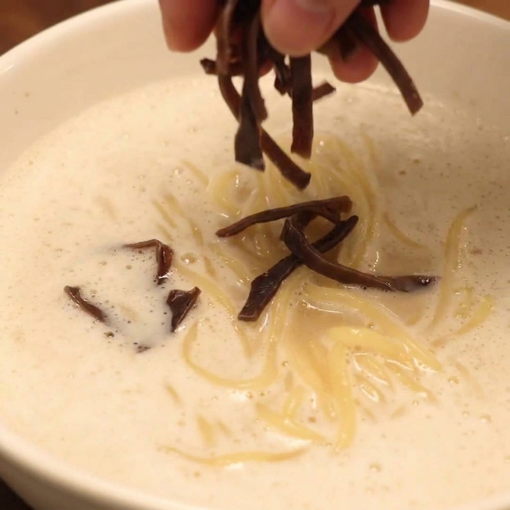 A fully assembled bowl of Chicken Paitan Foam Ramen topped with chashu, mushrooms, and fresh vegetables.