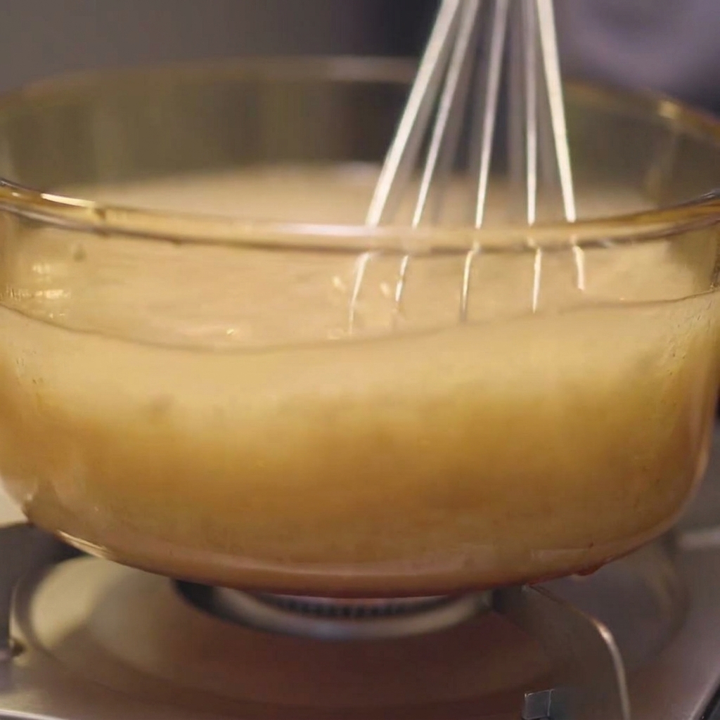 Pieces of kombu being submerged back into the chicken and water broth in a glass pot.