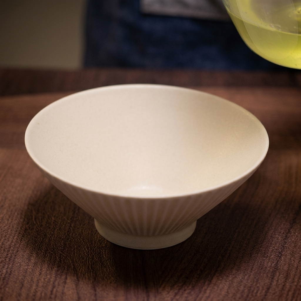 A ladle pouring steaming, clear broth into a white serving bowl, creating a swirling motion as it hits the salt base.