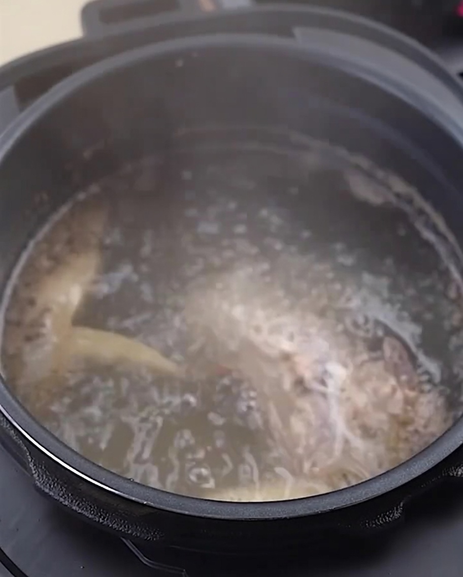 Rinsed chicken bones and feet in a stainless steel bowl.