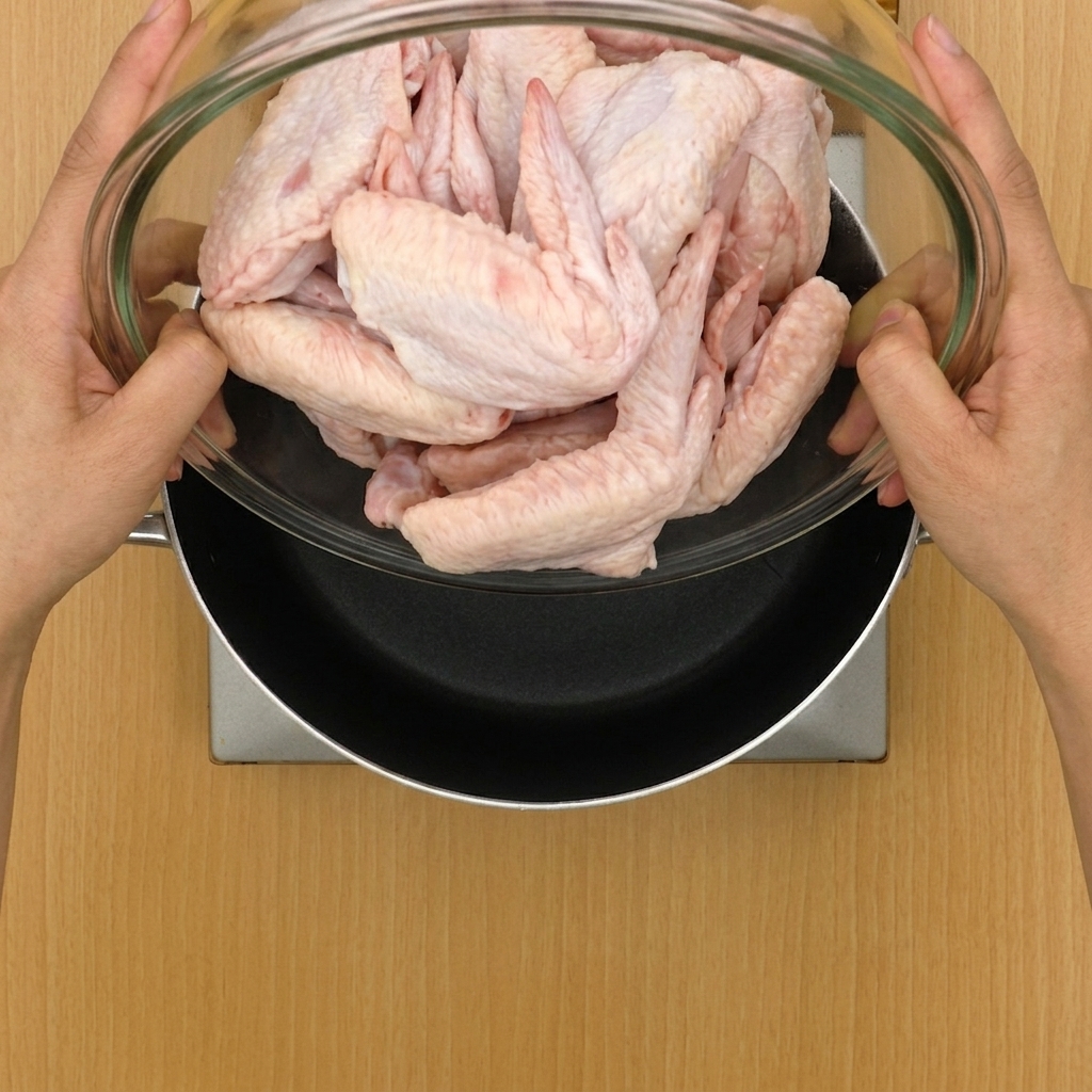 Chicken wings and aromatics being added to a large pot filled with water.