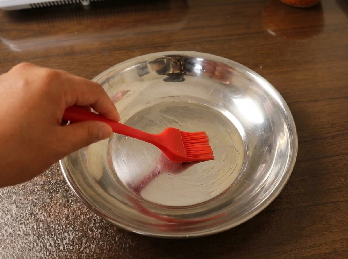A thin layer of batter spread evenly on a metal plate, ready to be steamed.