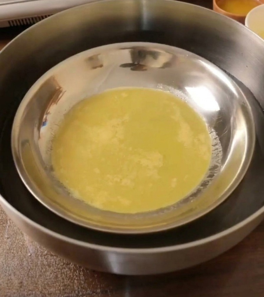 A cooked, elastic dough sheet inside a metal plate cooling in a water bath.