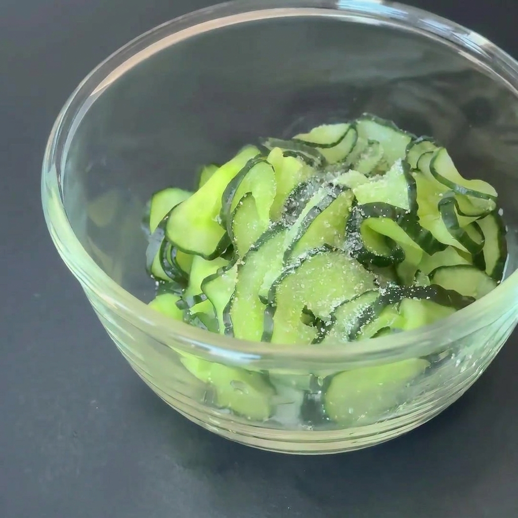 Cucumber slices in a glass bowl seasoned with sugar and apple cider vinegar.