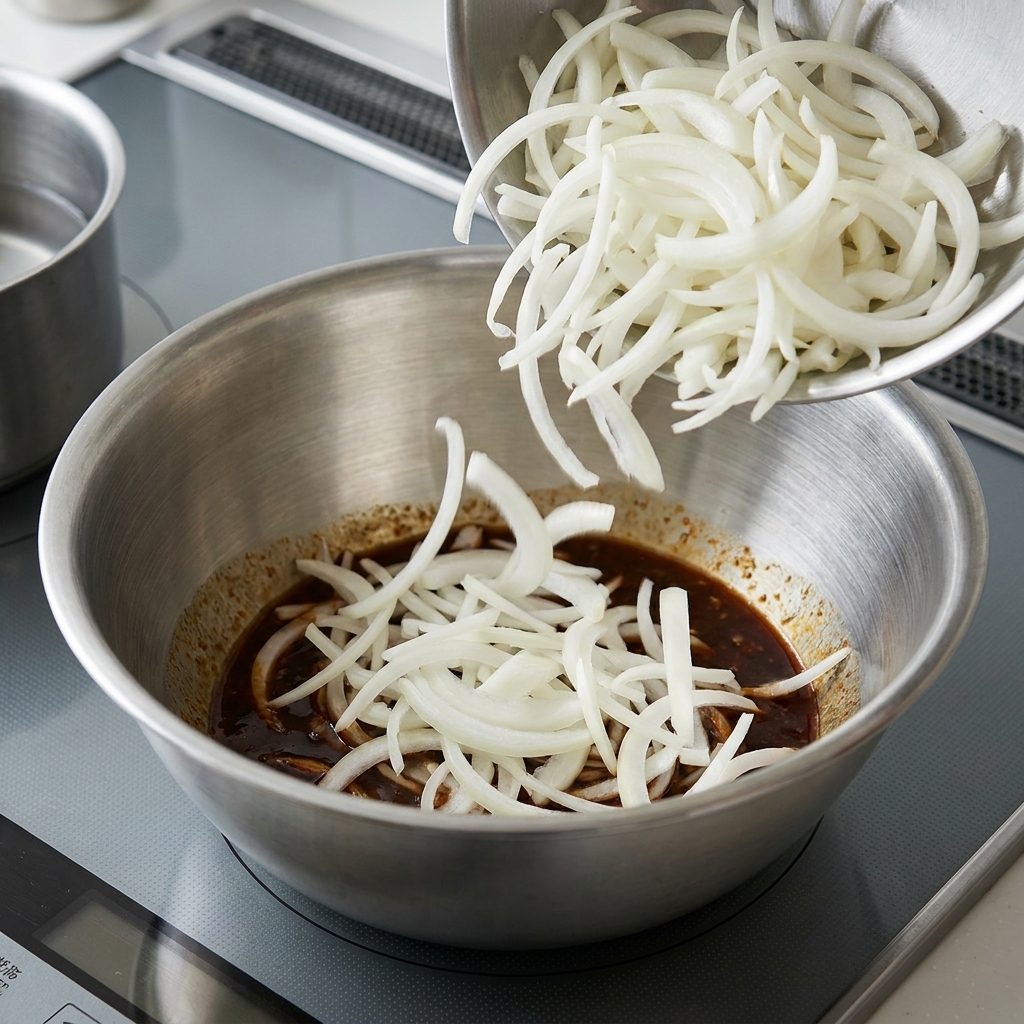 Cooked noodles being tossed with sesame sauce in a large bowl.