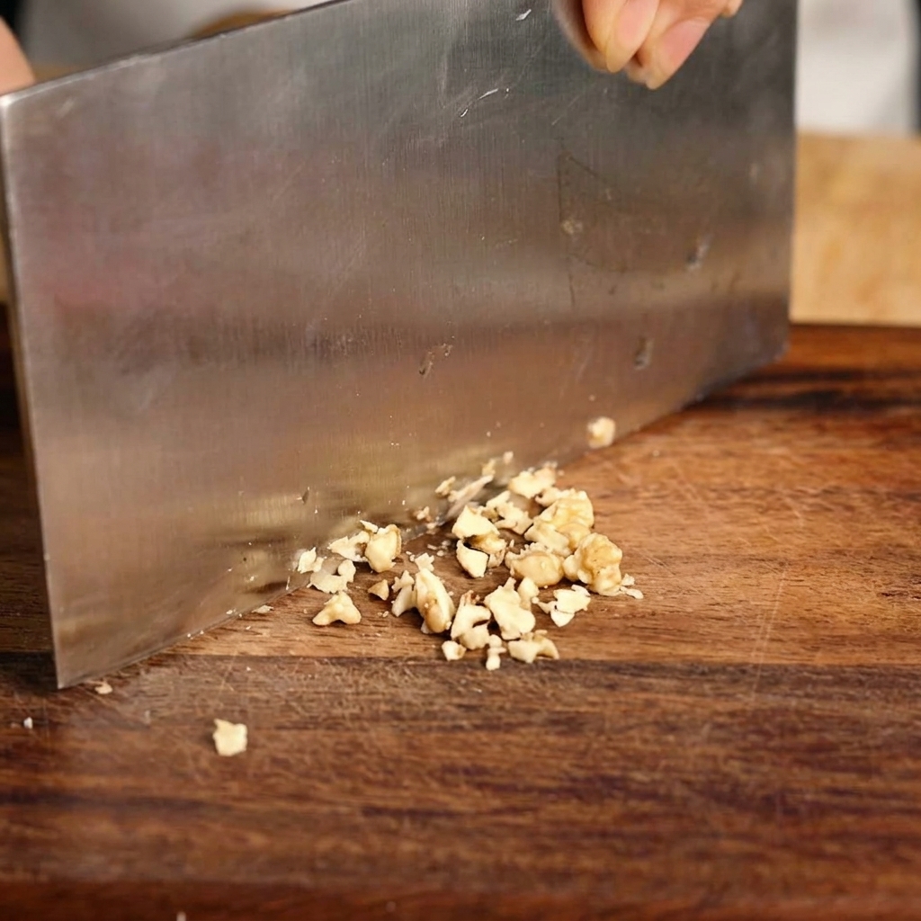Fresh green scallions being finely diced on a wooden cutting board with a knife.