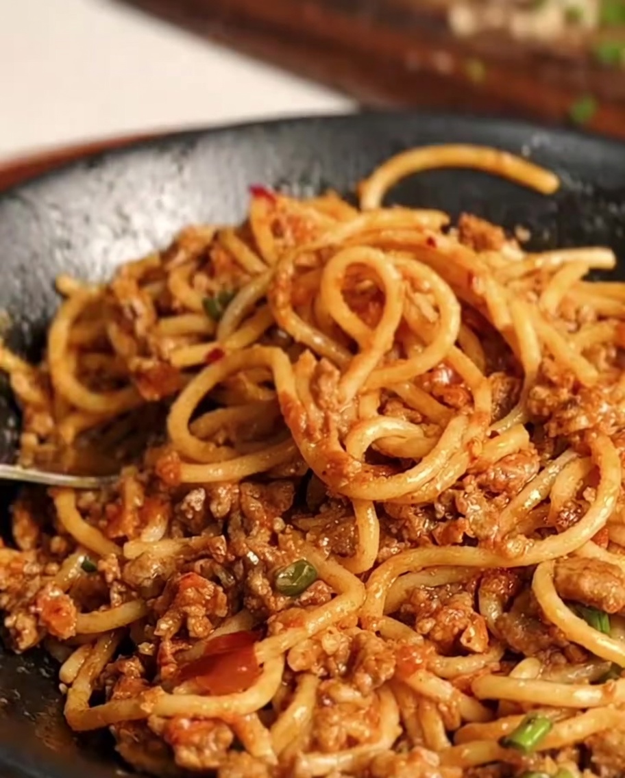 Tossing the spaghetti and meat sauce mixture together in the pan until uniform.