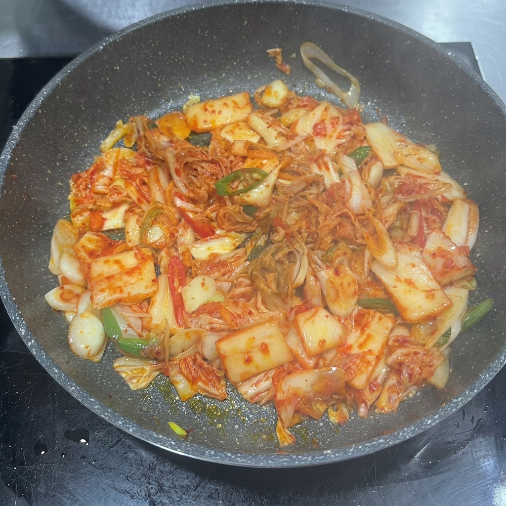 Chili paste, soy sauce, and sugar being added to the pan with kimchi.