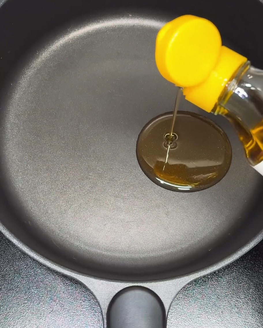 Sesame oil being poured into a non-stick pan.