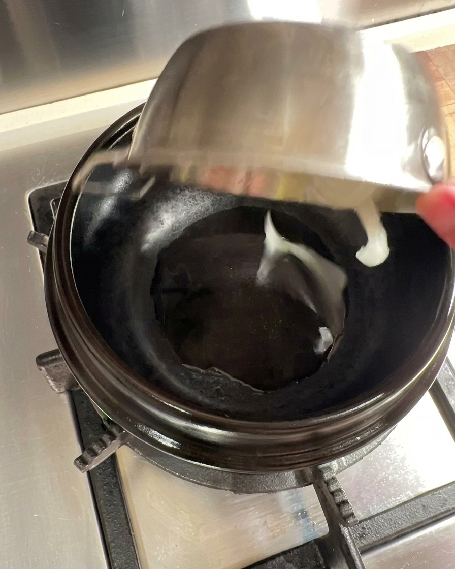 Onion slices being sautéed in a preheated stone pot with oil.