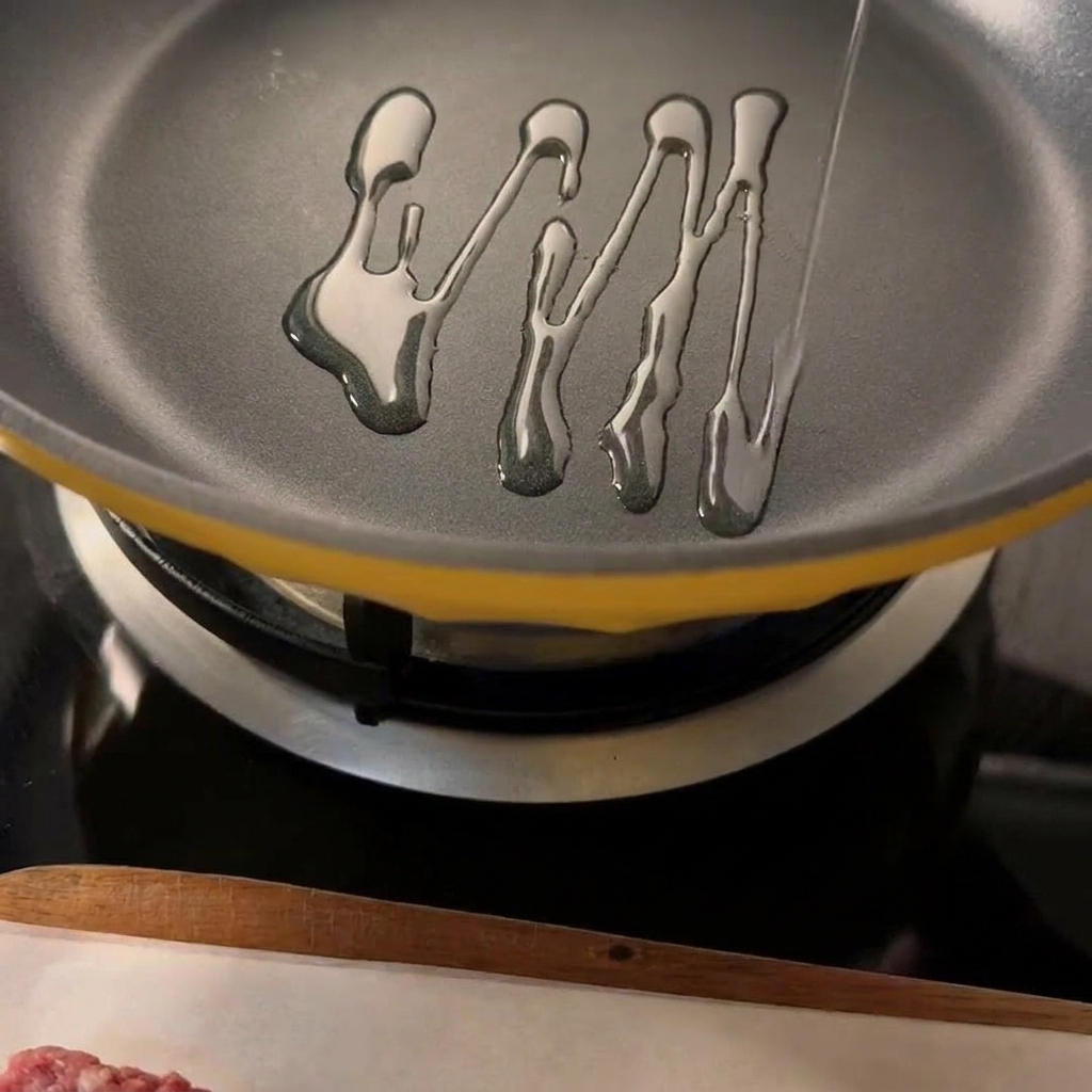 Two seasoned beef patties searing in a hot pan with visible oil.