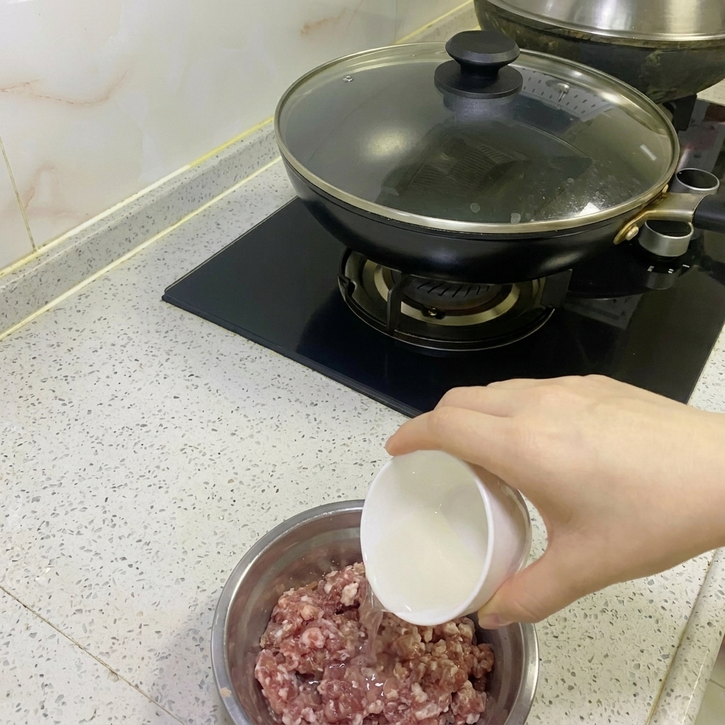 Clear onion and ginger water being poured into a bowl of raw minced meat.