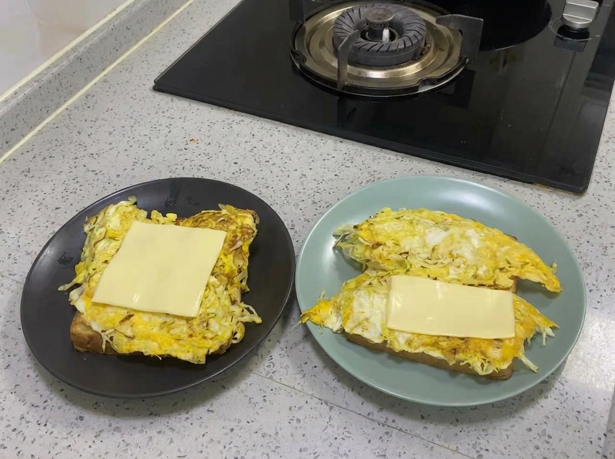A slice of yellow cheese melting on top of the cooked egg and cabbage layer.