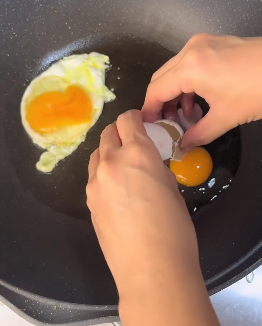 Eggs frying in a pan with hot oil.