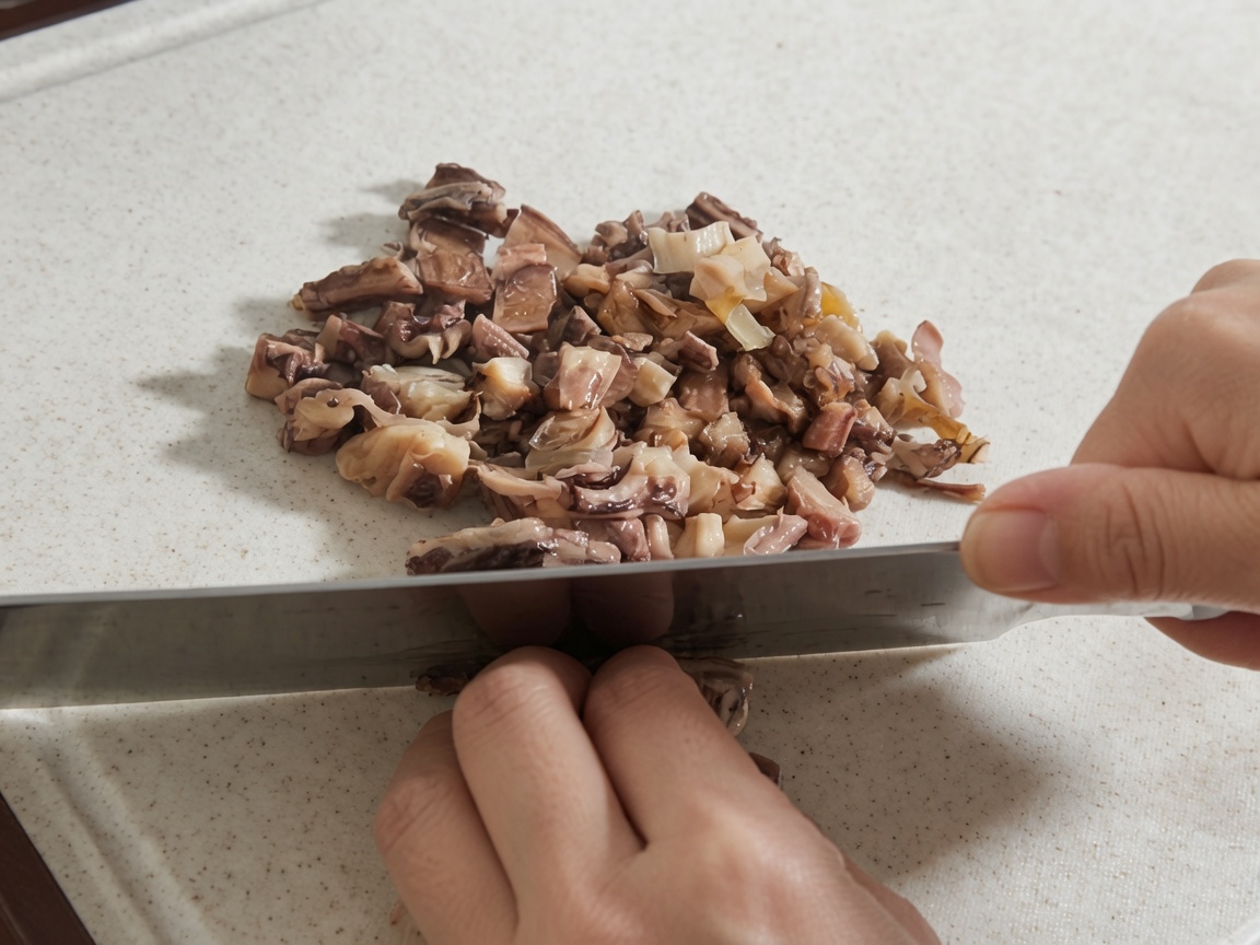 Hands using a large knife to chop rehydrated shiitake mushrooms and octopus pieces on a white cutting board.