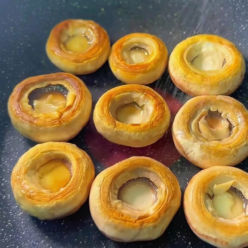 Mushroom caps in a pan seasoned with salt and pepper.