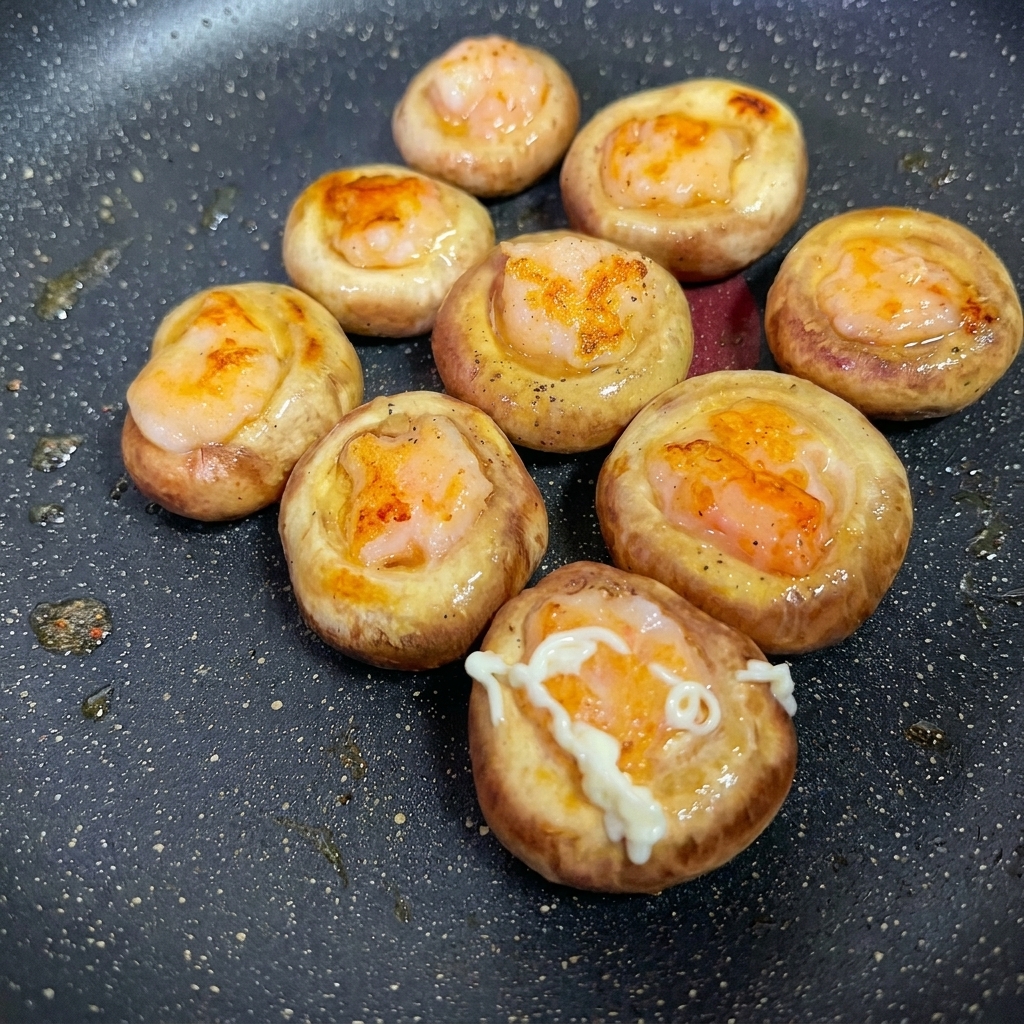 Close-up of dressing being squeezed onto the surface of cooked shrimp-stuffed mushrooms.