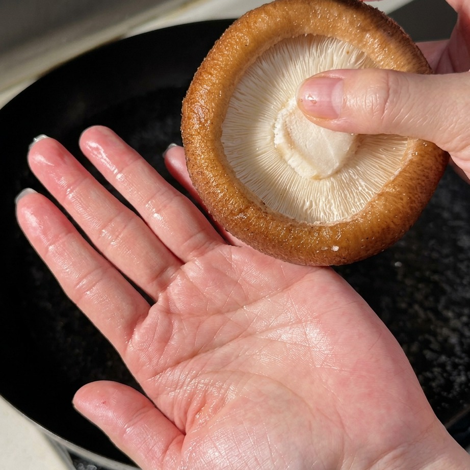 Large shiitake mushrooms being blanched in boiling water.