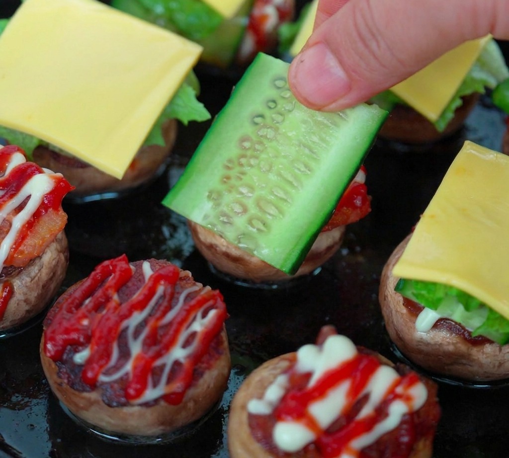 Assembly process showing a mushroom base layered with cucumber, lettuce, cherry tomato, and a cheese slice.