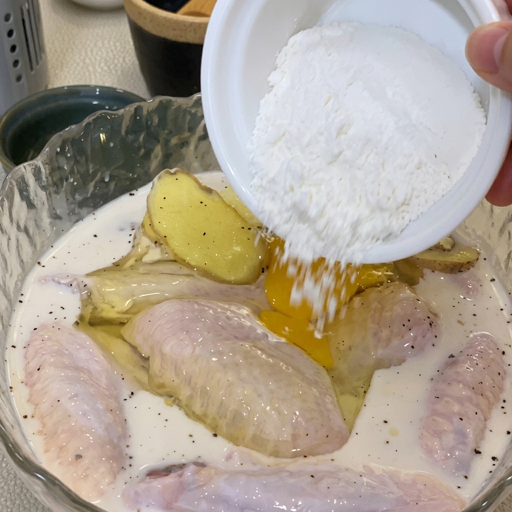 A hand mixing an egg and flour into the seasoned chicken bowl to create a batter.